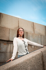 Wall Mural - A young model in her 20s in light-colored jeans walks around the city. Mild spring weather. Local tourism.