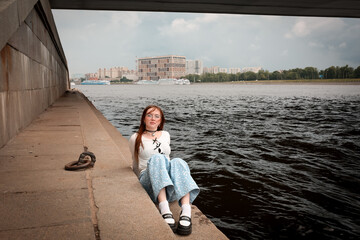 Wall Mural - A young model in her 20s in light-colored jeans walks around the city. Mild spring weather. Local tourism.