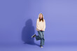 © deagreez - Smiling young girl in a casual sweater posing playfully against a vibrant purple background.