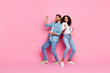 © deagreez - Young happy couple dancing joyfully together against a vibrant pink background while dressed in casual clothing