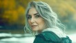 © Imagine Crane - A woman with striking gray hair gazes over her shoulder at a tranquil river surrounded by vibrant autumn foliage. The warm light of evening enhances the peaceful atmosphere