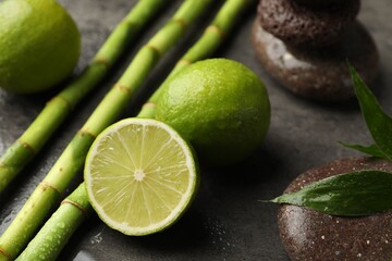 Wall Mural - Spa composition with wet limes, pebble stones, bamboo leaves and stems on grey table, closeup