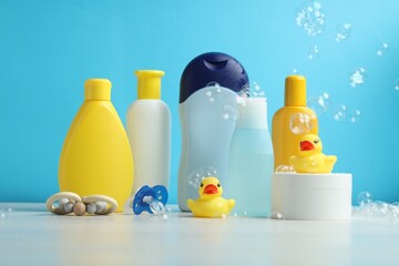 Wall Mural - Baby cosmetic products, pacifier, rubber ducks and flying bubbles on grey table against light blue background