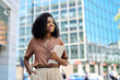 © insta_photos - Happy confident young African American professional woman, student, female entrepreneur, businesswoman looking away holding tab standing on business city street dreaming of future career. Copy space.