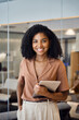 © insta_photos - Portrait of happy confident young African American business woman holding tablet standing in office. Smiling professional businesswoman executive manager looking at camera at work. Vertical portrait.
