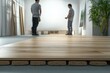 © stockphoto02 - Blurry image of two construction workers installing light brown wooden floor in a modern room.