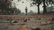 © musa - Man walking on autumn leaves path in park.