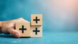 © ArtisticLens - Value add concept Hand place wooden cube with plus sign on light blue background Positive thinking o