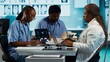 © DC Studio - African American doctor discussing with her nurses residents to find treatment options, showcasing teamwork and professionalism in the healthcare industry. Improving the services at clinic. Camera A.