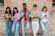 © Jose Calsina - Group Of Five Young Adults Engaged In Texting And Social Media On Their Smartphones While Standing In A Row Against A Wall Demonstrating Modern Communication And Digital Connection Among Friends