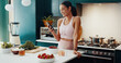 © CoetzeeRising/peopleimages.com - House, fitness and woman in kitchen, smartphone and smile with fruit, typing and online reading for diet. Person, apartment or athlete with sportswear, cellphone or nutrition with social media or app