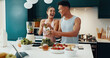 © CoetzeeRising/peopleimages.com - Laugh, ingredients and couple with smoothie in kitchen for diet, health and wellness together. Love, happy and young woman and man with vegetables and fruit for nutrition juice breakfast in home.