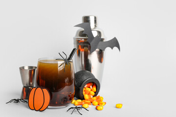 Wall Mural - Glass of delicious cocktail for Halloween with candy corns and spiders on light background, closeup