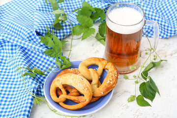 Plate with soft pretzels and glass of beer on white background