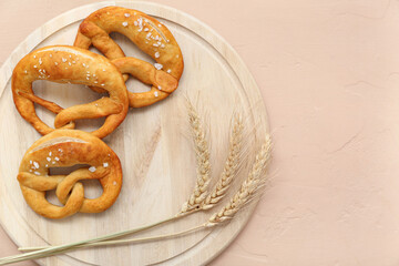 Wall Mural - Wooden board with soft pretzels and wheat on beige background