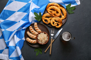 Wall Mural - Tasty sausages, flag of Bavaria, pretzels, sauerkraut and mug with beer on black background. Oktoberfest celebration