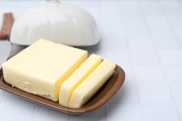 Wall Mural - Cut tasty butter in dish on white tiled table, closeup. Space for text