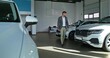 © m-art - A stylish man chooses a car at a car dealership. He walks between the cars and examines them with a serious look