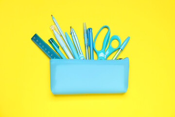 Wall Mural - Pencil case and different stationery on yellow background, flat lay