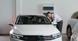 © m-art - A family with a child is sitting in a car in a showroom. The car dealership manager is talking to them, standing nearby