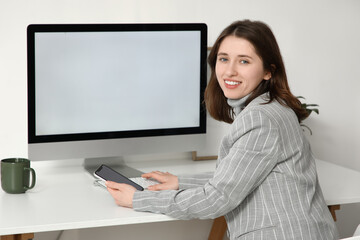 Young businesswoman working with blank computer at table in office
