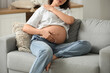 © Pixel-Shot - Young pregnant woman suffering from neck pain on sofa at home, closeup