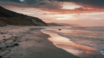 Poster - Serene shoreline at low tide under a colorful sunset with soft waves lapping at wet sandy beach and distant coastal hills in warm tones.