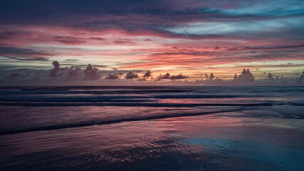 Aufkleber - Twilight seascape features a vivid gradient of purples, pinks, and blues with reflective wet sand in the foreground and clouds scattered above.