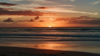 Aufkleber - Golden sunset reflecting on calm ocean waves near sandy beach with scattered clouds and vibrant orange, pink, and blue hues in the sky.