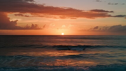 Poster - Vibrant golden sunset reflecting on calm ocean waves with soft clouds in pink and orange hues, sun positioned at horizon creating serene ambiance.