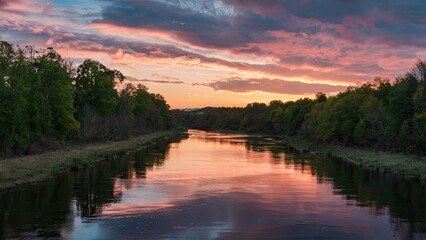 Poster - Serene sunset over a calm river reflecting vibrant pink and purple clouds with lush green trees framing the tranquil waterway.
