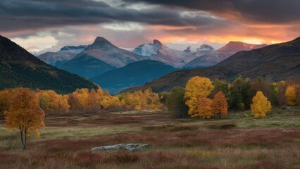 Poster - Majestic mountain landscape at sunset with vibrant autumn trees in orange and yellow hues, set against dark clouds and a serene valley view.