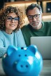 © felix_brönnimann - Couple managing personal finances together with a laptop, focusing on budgeting and savings using a piggy bank as a symbol of financial planning and investment.