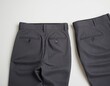 © Viktor Petrushenko - Two pairs of stylish gray dress pants laid out, showcasing their tailored design and buttoned back pockets.