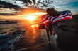 © NDABCREATIVITY - Happy woman holding american USA flag and running on the beach. Independence Day, travel concept