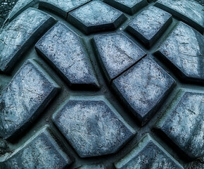 Wall Mural - Tire Tread Texture: Close-up view of a rugged tire tread, showcasing its deep, geometric pattern and textured surface. The image offers a captivating study in contrasts between light and shadow.