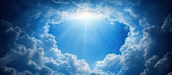 Poster - Bright blue sky with radiant sunlight breaking through fluffy white clouds, creating a heavenly atmosphere in the center of the image.