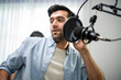 © Kawee - Caucasian young DJ man singing a song on microphone to broadcasting.