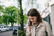 © contrastwerkstatt - Young woman talking on phone on city sidewalk