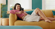 © PeakPoints/peopleimages.com - Phone, relax and happy girl on sofa, typing message and online post on social media profile. Mobile, home and woman on app for communication, check notification and playing games on internet to chill