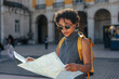© bernardbodo - Young tourist woman reading a map in a city square
