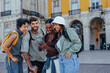 © bernardbodo - Happy tourists using smart phone and laughing in lisbon, portugal