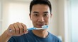 © Interactive Arts - Satisfied asian korean man with toothbrush brushing teeth in bathroom, dental and oral care concept