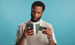 © peopleimages.com - Confused, phone and black man with credit card in studio for online shopping, digital purchase or order. Blue background, scam and person on smartphone for banking app, internet payment and ecommerce
