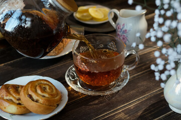 Sticker - Tea time. Pouring brewed black tea from teapot into cup. Morning breakfast with tea and pastries. 