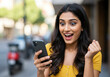© ProArt Studios - Overjoyed Indian Woman Using Phone to Celebrate a Victory, Radiating Happiness and Success