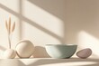 © VICHIZH - Minimalistic home decor featuring a soft green bowl, beige stones, and decorative grass in a serene interior setting with natural light