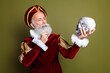 © deagreez - Senior Man in Royal Costume Holding Skull Performing Iconic Scene Against Khaki Background, think to be or not to be