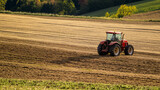 Czerwony traktor na dużym polu rolniczym podczas zachodu słońca