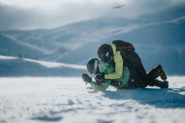 Wall Mural - Two individuals wearing winter gear enjoy a moment of connection and joy amidst a snowy landscape, surrounded by breathtaking mountain views under a serene sky.